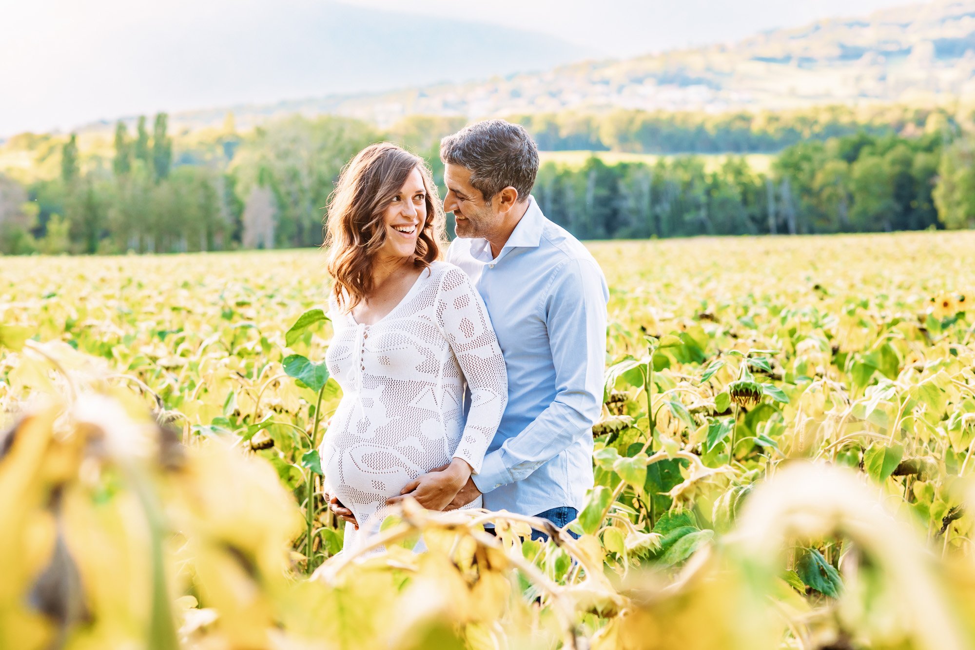 Couple embrace in outdoor maternity photo shoot with Jura Mountains behind